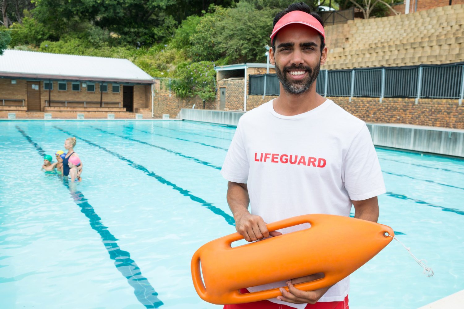 Two certified Red Cross lifeguards in uniform at the edge of a busy pool